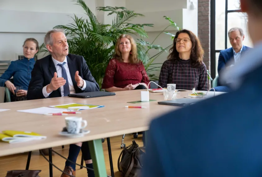 Een groep mensen zit aan tafel en voert een gesprek